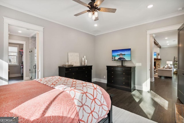 bedroom with ensuite bath, ceiling fan, a fireplace, crown molding, and dark wood-type flooring