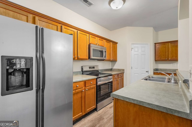 kitchen with light wood-type flooring, appliances with stainless steel finishes, and sink