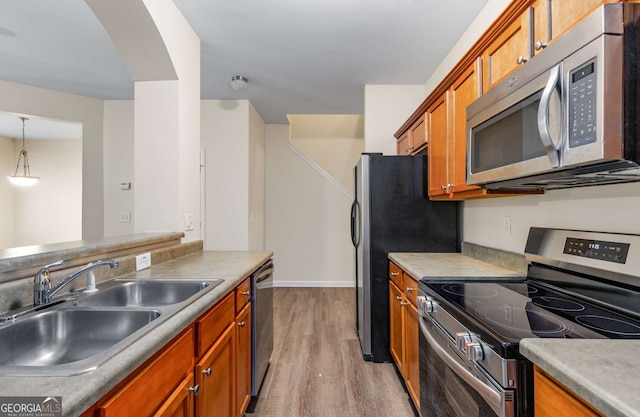 kitchen featuring pendant lighting, light wood-type flooring, appliances with stainless steel finishes, and sink