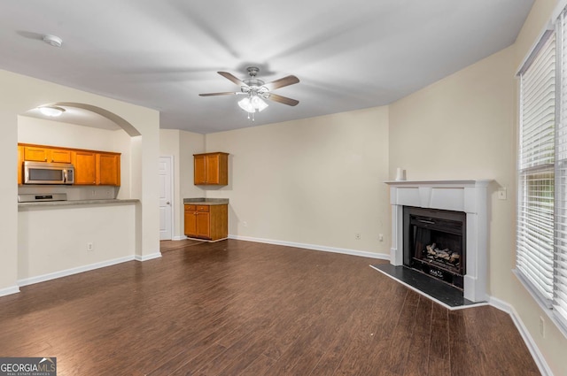 unfurnished living room featuring dark wood-type flooring and ceiling fan