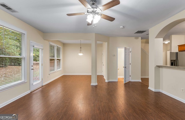 unfurnished living room featuring dark wood-type flooring, ceiling fan, and a healthy amount of sunlight