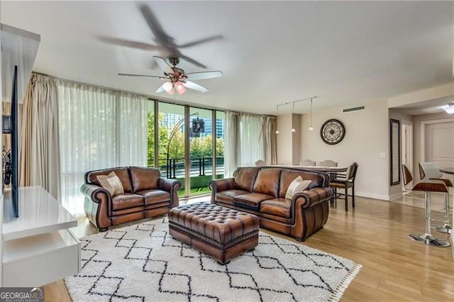 living room with ceiling fan, light hardwood / wood-style floors, rail lighting, and expansive windows