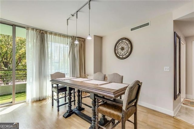 dining room with rail lighting and light hardwood / wood-style flooring