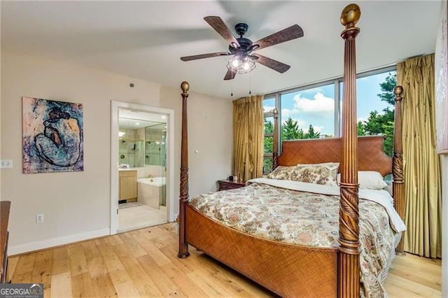 bedroom featuring light wood-type flooring, connected bathroom, a wall of windows, and ceiling fan