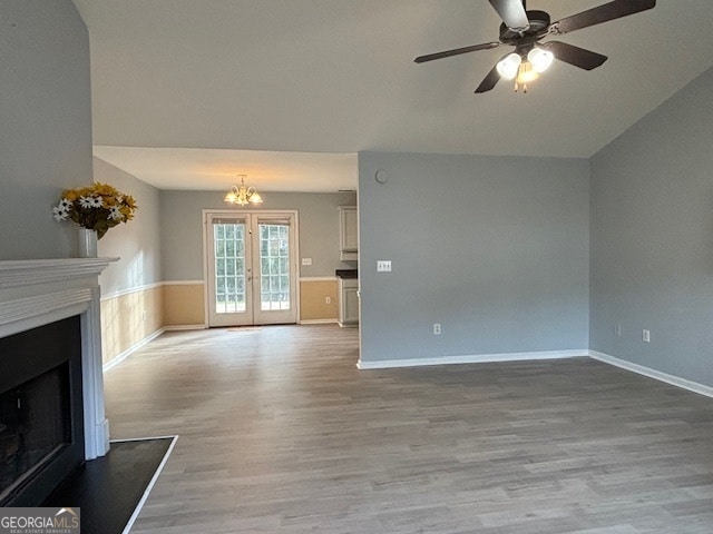 unfurnished living room with french doors, ceiling fan with notable chandelier, light hardwood / wood-style floors, and lofted ceiling