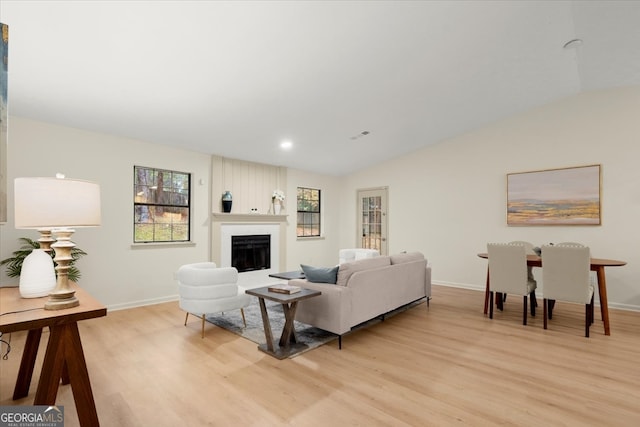 living room featuring a large fireplace, light wood-type flooring, and vaulted ceiling