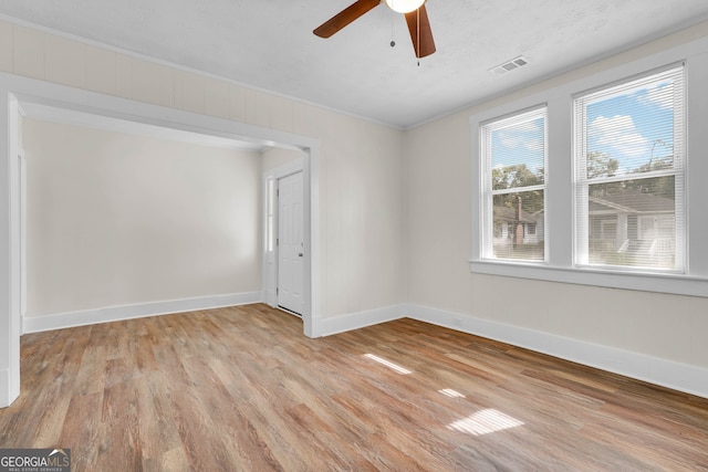 empty room with light wood-type flooring, a textured ceiling, ceiling fan, and crown molding