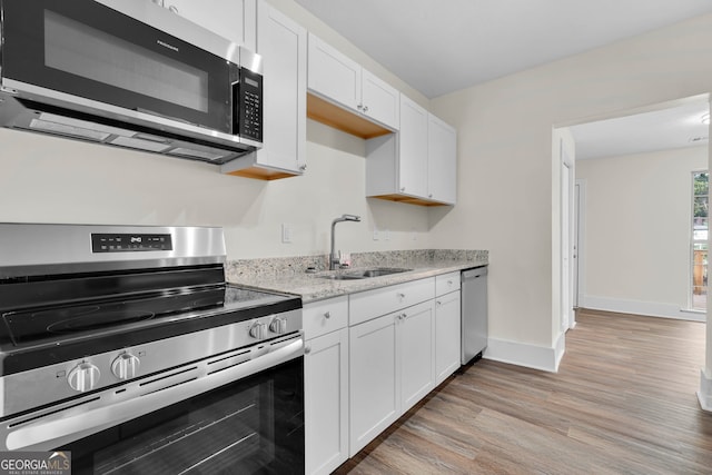 kitchen featuring light hardwood / wood-style flooring, appliances with stainless steel finishes, sink, and white cabinets