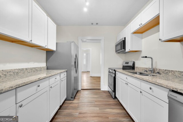 kitchen with white cabinets, light wood-type flooring, appliances with stainless steel finishes, and sink