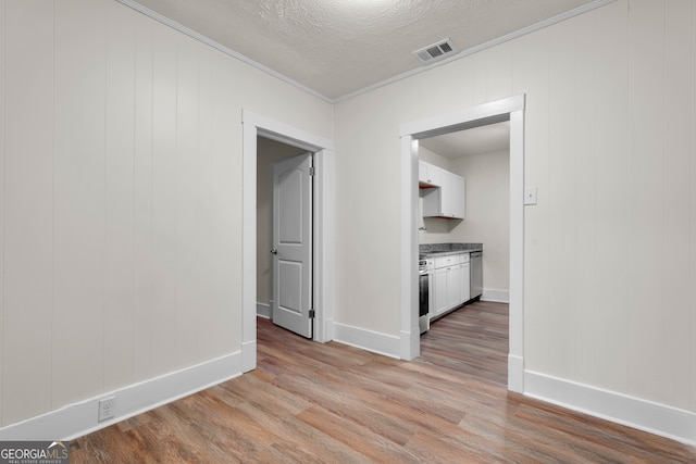 interior space featuring ornamental molding, light hardwood / wood-style floors, and a textured ceiling