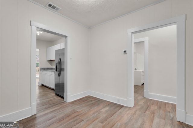 corridor featuring ornamental molding, light hardwood / wood-style floors, and a textured ceiling