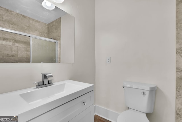 bathroom with toilet, vanity, and a shower with shower door