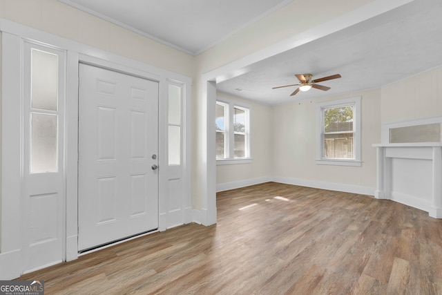 foyer entrance with ornamental molding, light hardwood / wood-style flooring, and ceiling fan