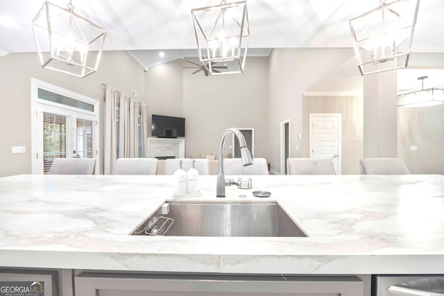 kitchen with light stone counters, sink, and crown molding