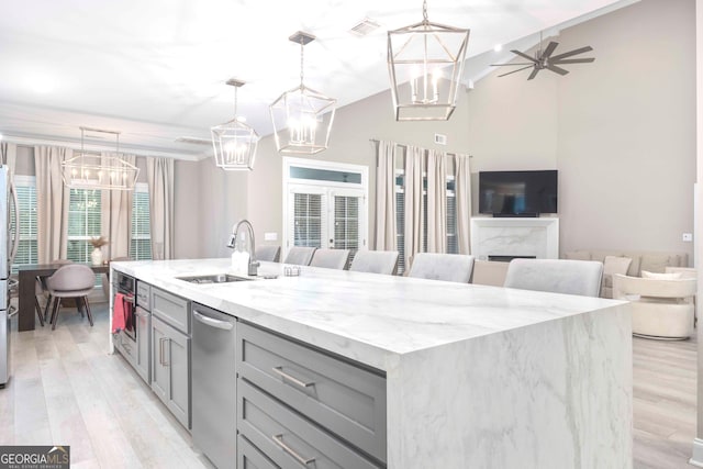 kitchen featuring decorative light fixtures, a center island with sink, and light hardwood / wood-style flooring