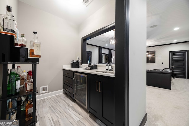 bar with beverage cooler, sink, and light carpet