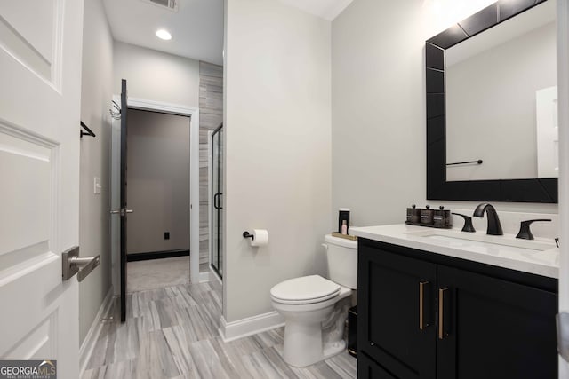 bathroom featuring a shower with shower door, vanity, and toilet