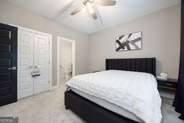 bedroom featuring ensuite bathroom, ceiling fan, a closet, and light colored carpet