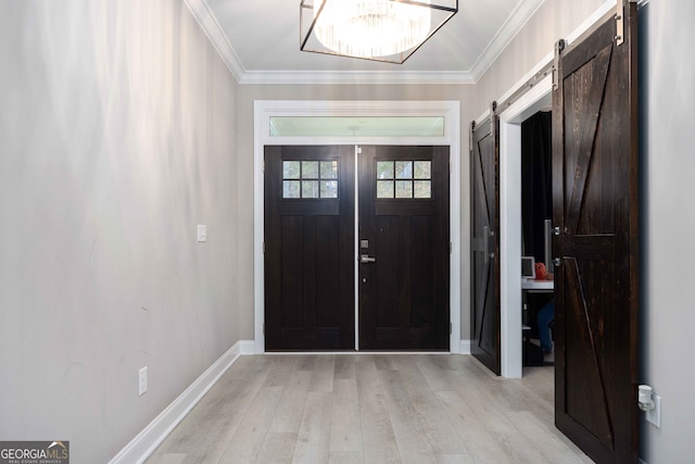 entrance foyer featuring a barn door, light hardwood / wood-style floors, and ornamental molding