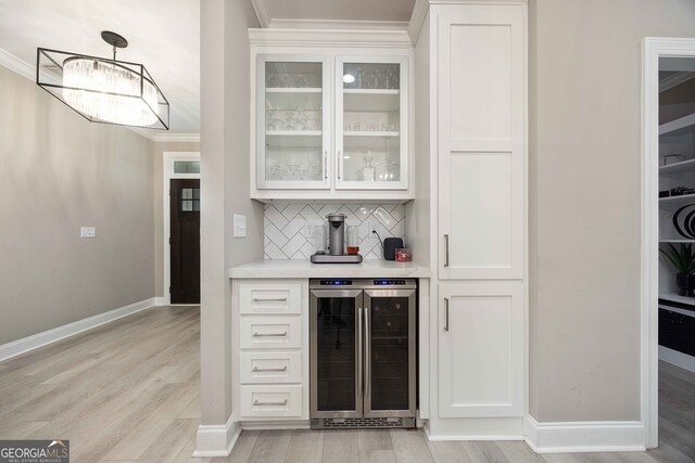 bar featuring tasteful backsplash, beverage cooler, light hardwood / wood-style floors, and white cabinets