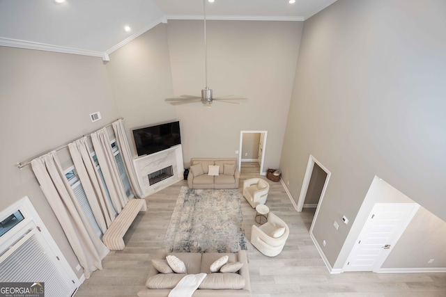 living room featuring ornamental molding, ceiling fan, and a high ceiling