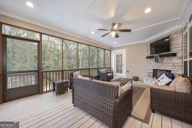 sunroom with ceiling fan and a fireplace