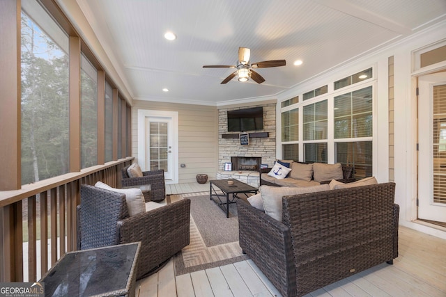 sunroom featuring an outdoor stone fireplace and ceiling fan