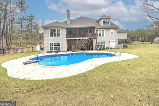 back of property featuring a lawn, a patio area, a sunroom, and a fenced in pool