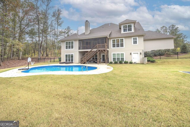 back of house with a sunroom, a lawn, and a fenced in pool