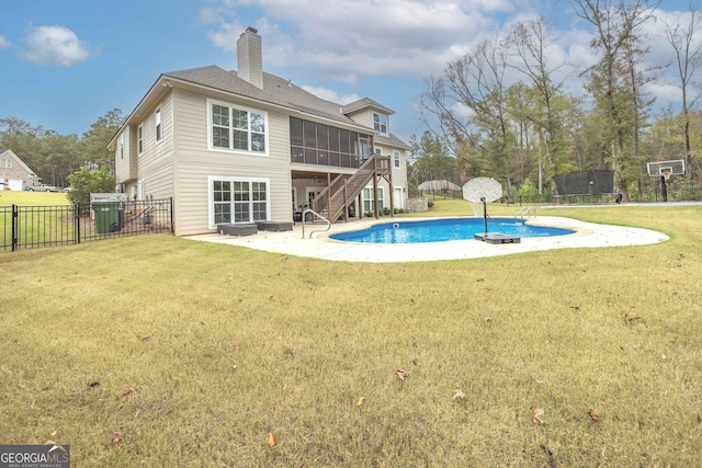 back of property featuring a sunroom, a trampoline, a fenced in pool, a patio, and a yard