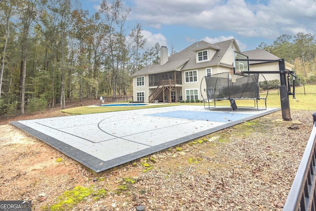 view of sport court featuring a trampoline and a lawn