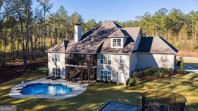 rear view of property with a lawn and a fenced in pool