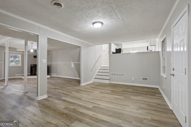 basement featuring ornamental molding, a textured ceiling, and light wood-type flooring