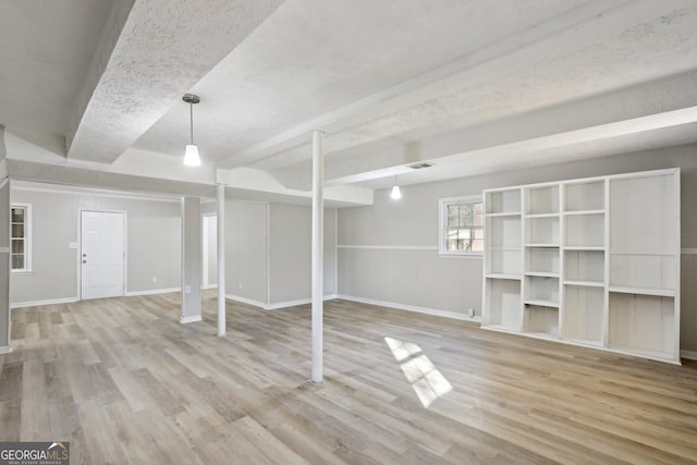 basement with a textured ceiling and light hardwood / wood-style flooring