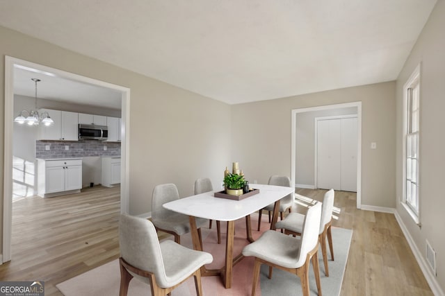 dining space featuring light hardwood / wood-style flooring and an inviting chandelier