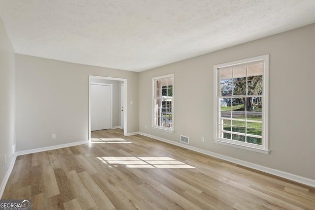 unfurnished room with a textured ceiling and light hardwood / wood-style flooring