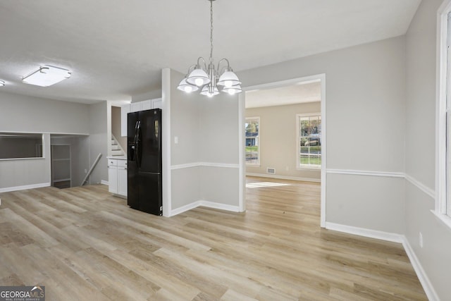 unfurnished dining area with a chandelier and light wood-type flooring