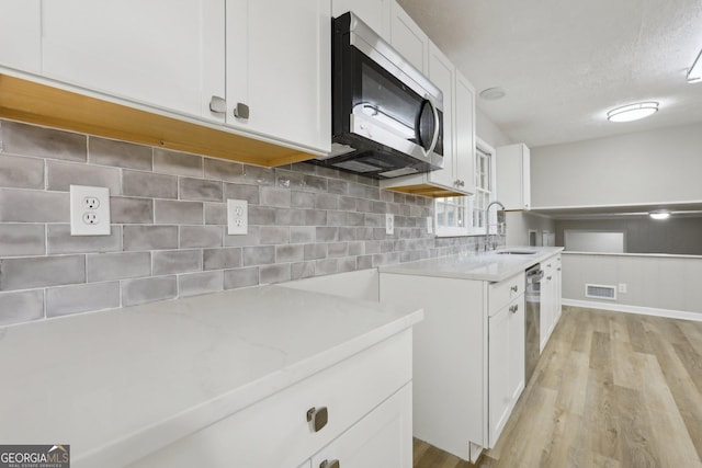 kitchen featuring appliances with stainless steel finishes, backsplash, sink, light hardwood / wood-style flooring, and white cabinets