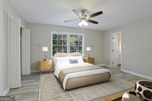 bedroom with ceiling fan, light wood-type flooring, and a textured ceiling