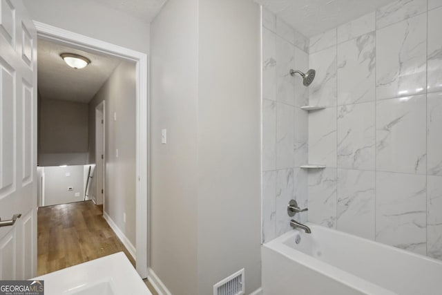 bathroom with hardwood / wood-style flooring and tiled shower / bath combo