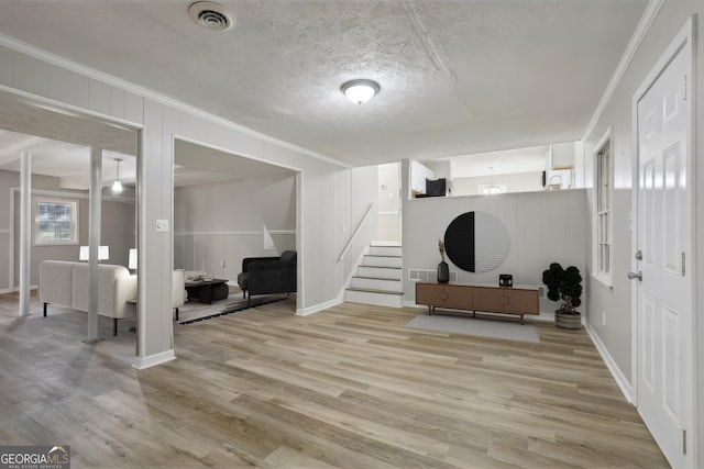 foyer entrance featuring a textured ceiling, light hardwood / wood-style floors, and crown molding