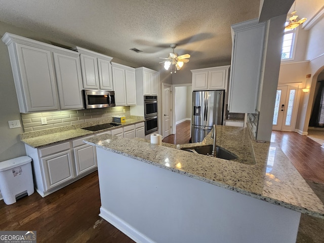 kitchen with tasteful backsplash, a textured ceiling, stainless steel appliances, sink, and white cabinets