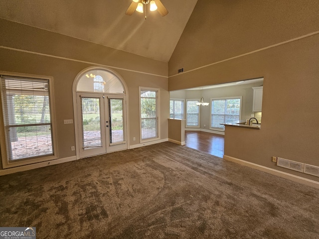 unfurnished living room featuring ceiling fan, dark carpet, plenty of natural light, and high vaulted ceiling