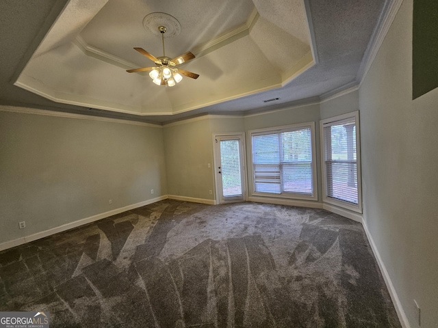 unfurnished room featuring a tray ceiling, dark carpet, ceiling fan, and ornamental molding