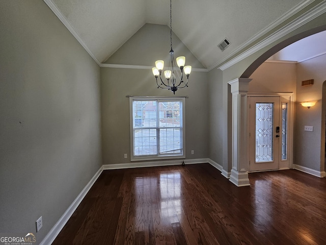 entrance foyer with ornate columns, vaulted ceiling, dark wood-type flooring, crown molding, and a notable chandelier