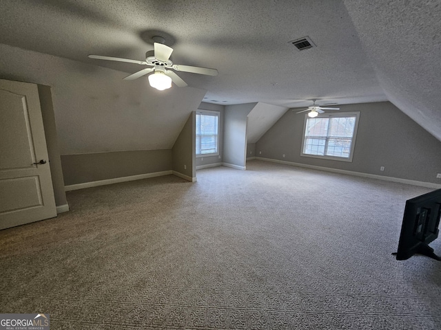 bonus room featuring a textured ceiling, vaulted ceiling, ceiling fan, and a healthy amount of sunlight