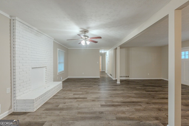 unfurnished living room featuring a brick fireplace, hardwood / wood-style floors, a wealth of natural light, and a textured ceiling