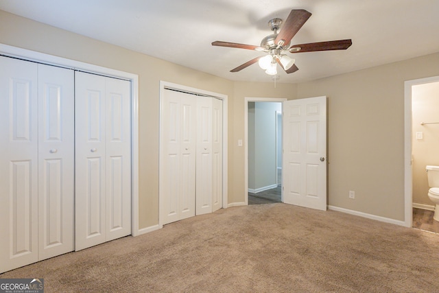 unfurnished bedroom with carpet floors, two closets, ceiling fan, and ensuite bathroom