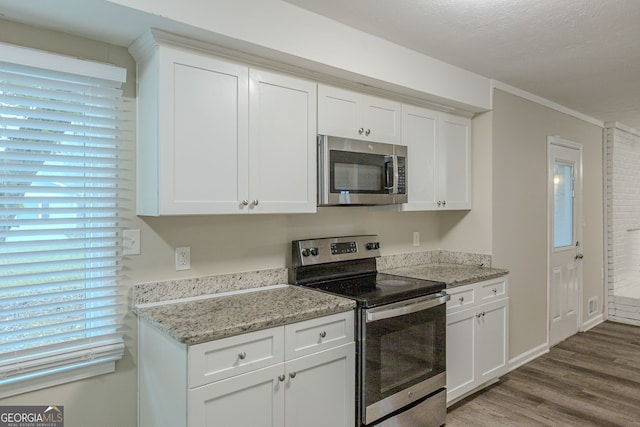 kitchen with stainless steel appliances, light hardwood / wood-style floors, white cabinets, and light stone countertops