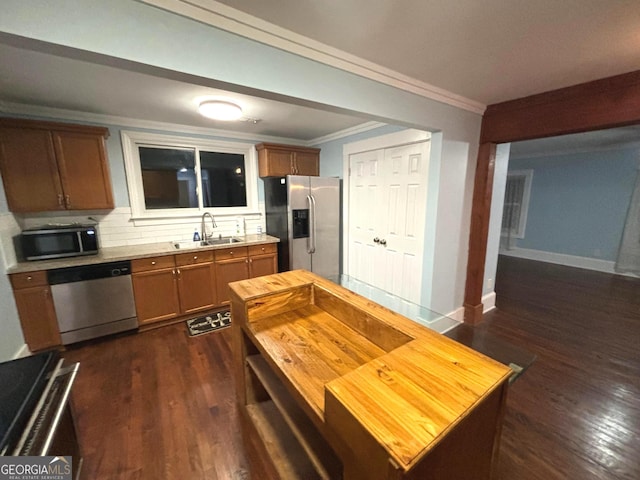 kitchen featuring sink, crown molding, appliances with stainless steel finishes, backsplash, and dark hardwood / wood-style floors